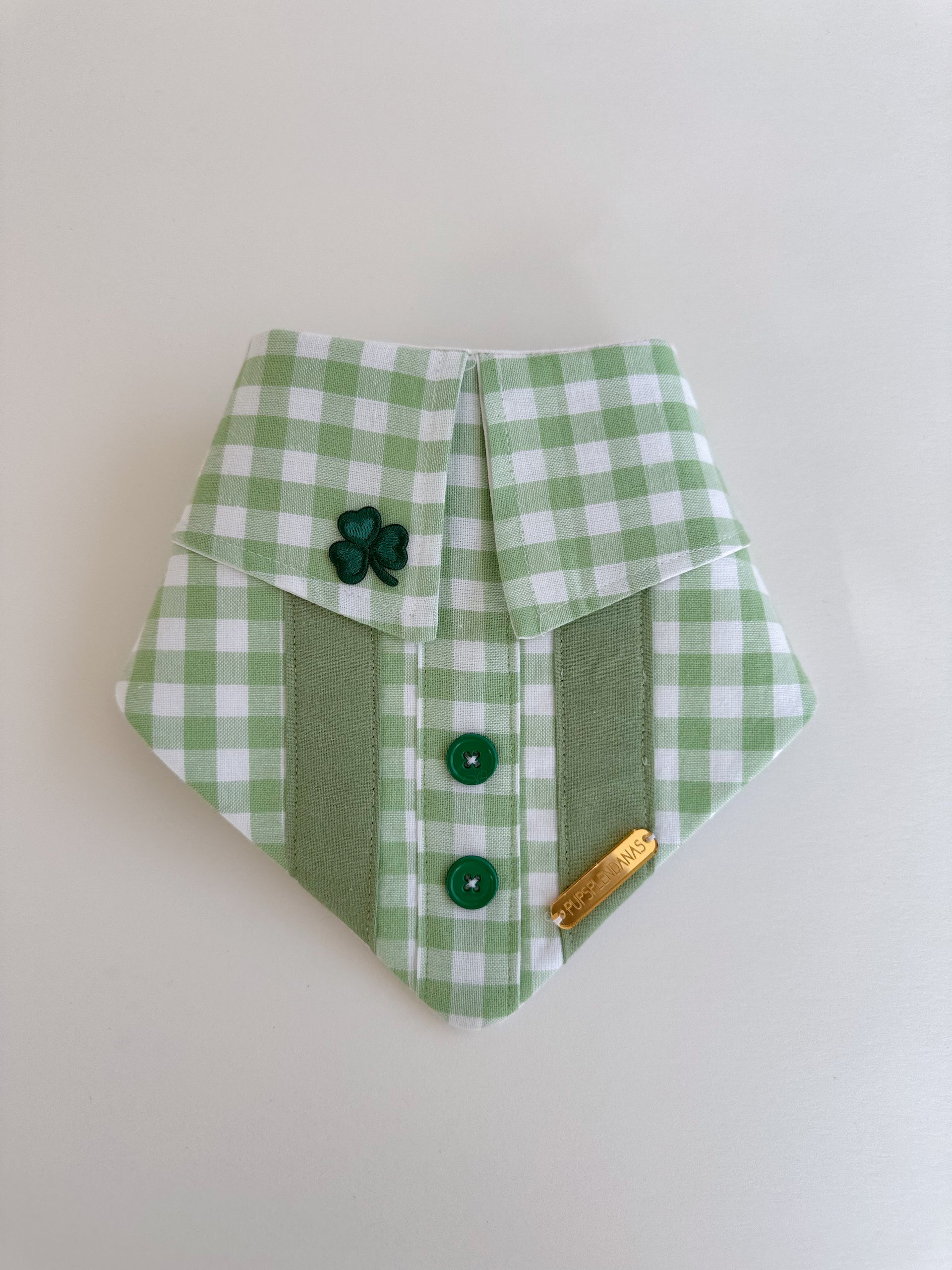 Green and white checkered fabric with buttons and a shamrock on a beige background