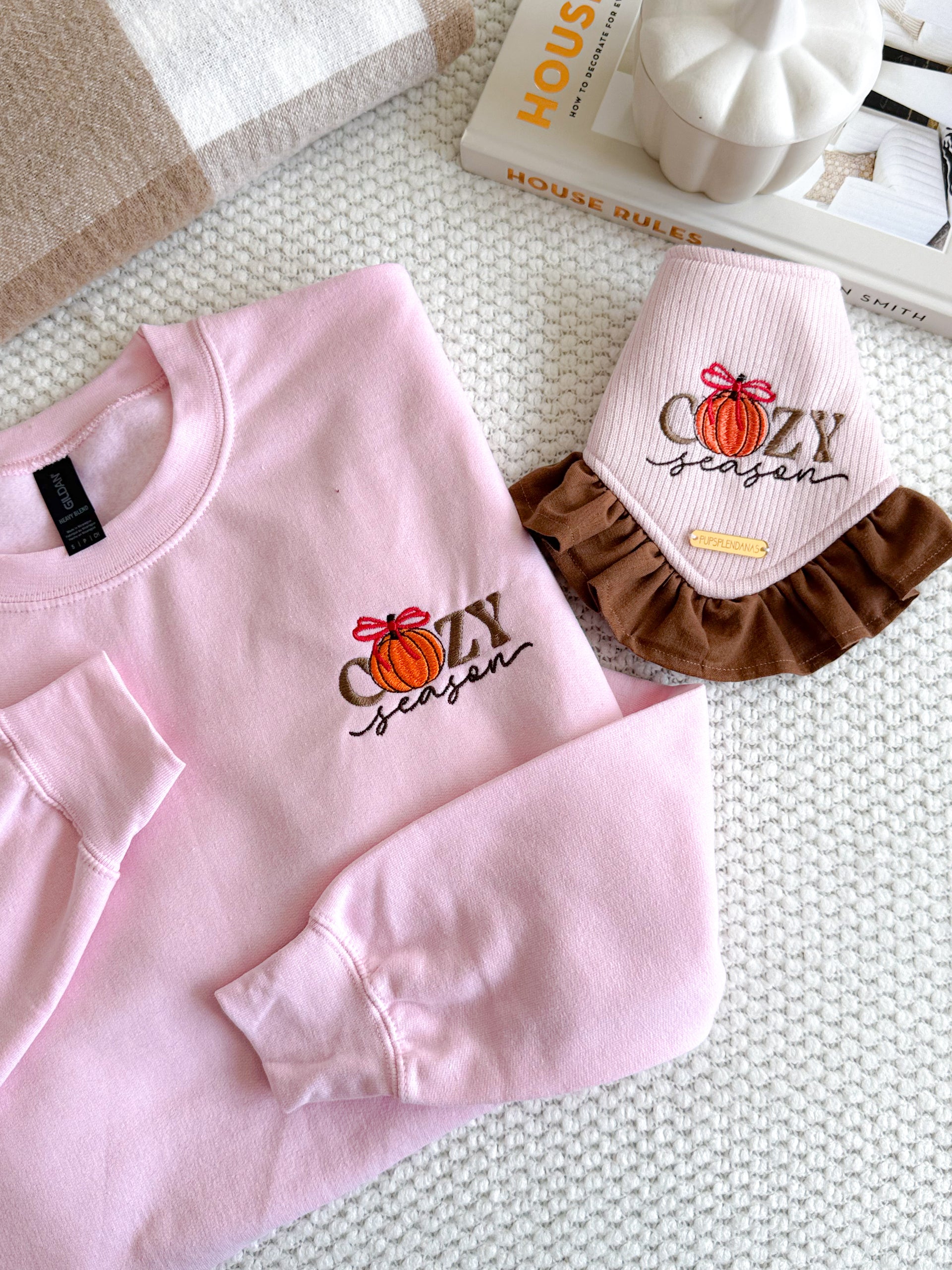 Pink sweatshirt with 'Cozy Season' design on a textured surface