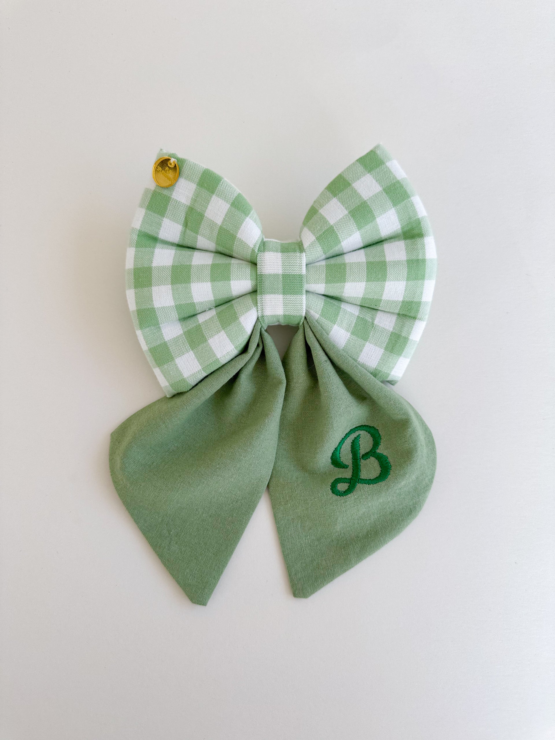 Green checkered bow with a letter on a light background
